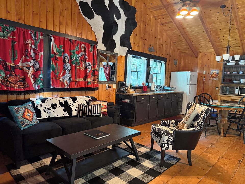 Open cabin living space with western curtains, full kitchen, and cowhide furnishings.