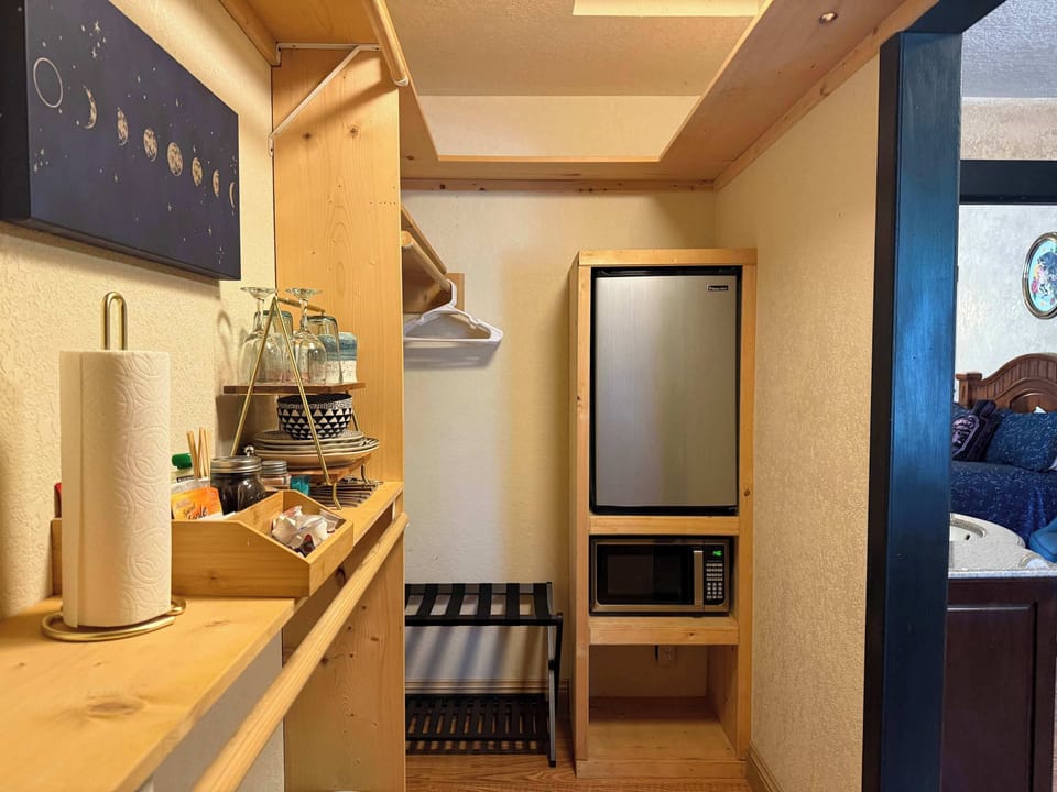 Kitchenette nook with fridge, microwave, and coffee setup.