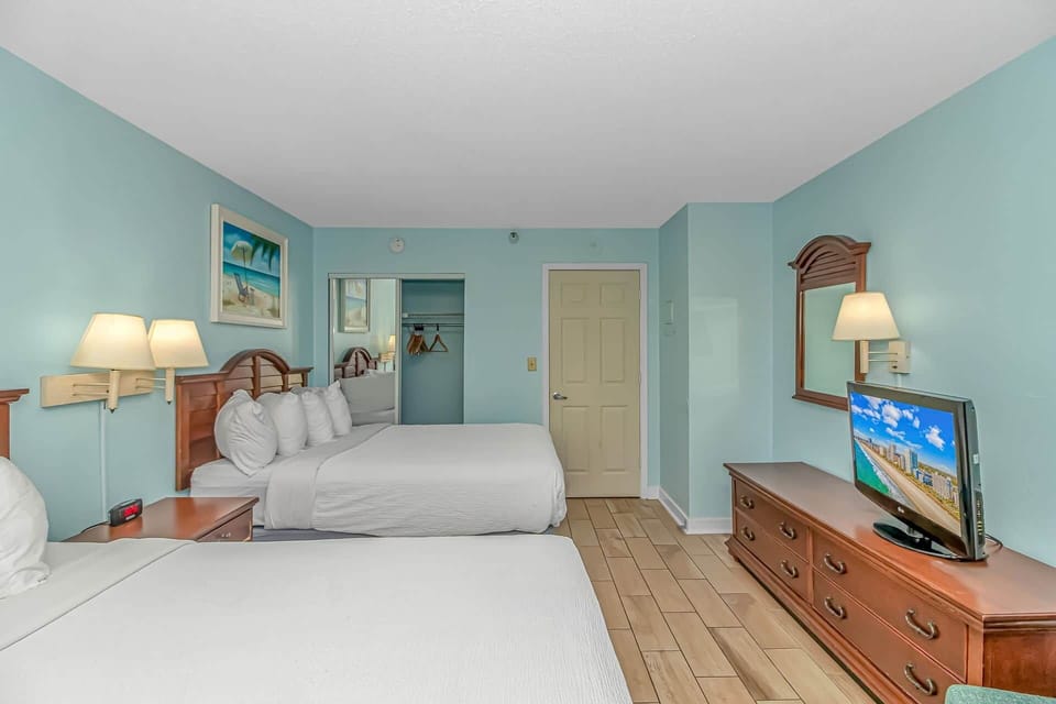 Bright and spacious bedroom with two comfy queen beds, coastal décor, and plenty of room to relax af