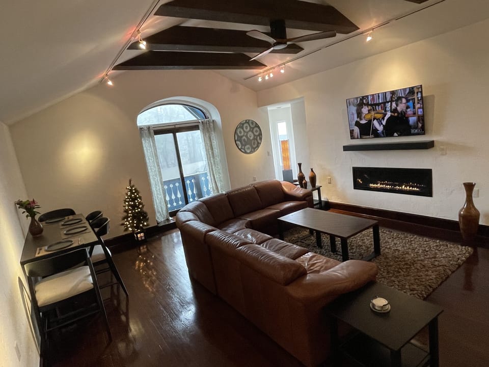 Modern living area with linear gas fireplace, big screen TV and dining area.