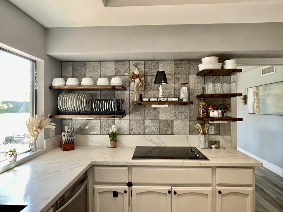 custom designer tile backsplash behind cooktop, & handmade floating shelving.