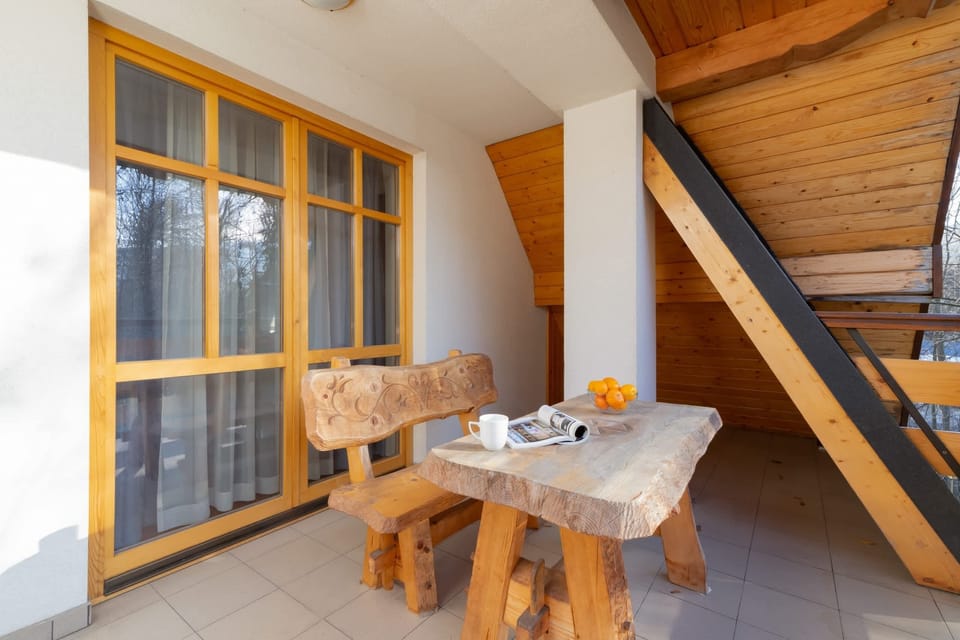 A balcony with a wooden couch and a neatly arranged coffee table, offering a relaxing environment.