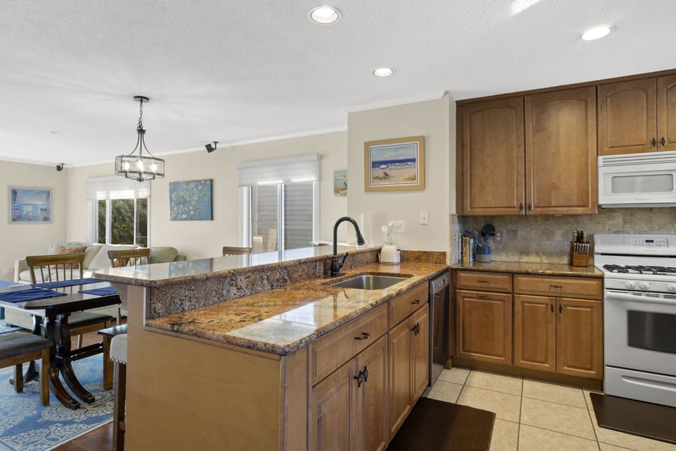 39562 Admiral Rd, North Bethany - kitchen - A wide perspective of the gourmet kitchen showcasing the extensive wood cabinetry, premium stainless steel appliances, and the generous counter space perfect for vacation meal prep.