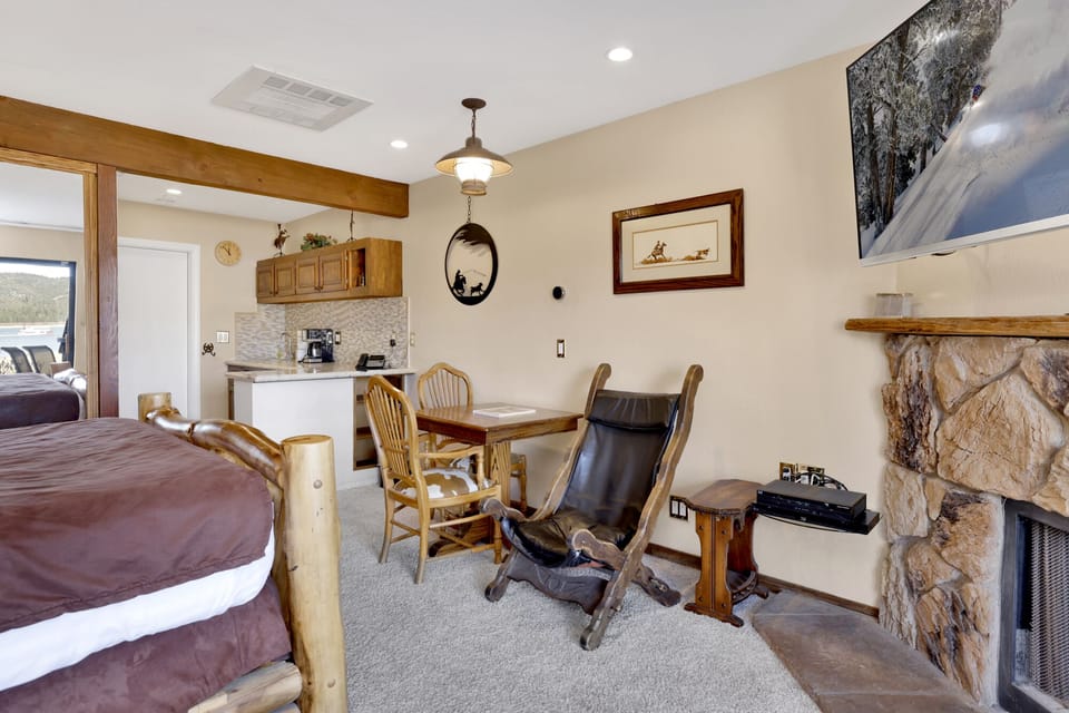 Cozy mountain living room with a stone fireplace, comfy seating, and smart TV—perfect for relaxing evenings, movie nights, and warm cabin vibes after outdoor adventures.