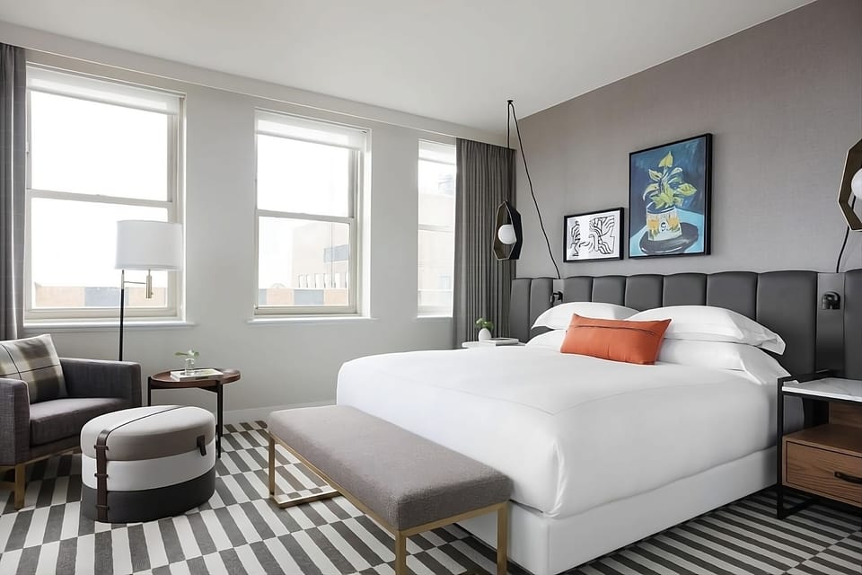 Unwind in crisp linens beside bright windows and cozy seating.