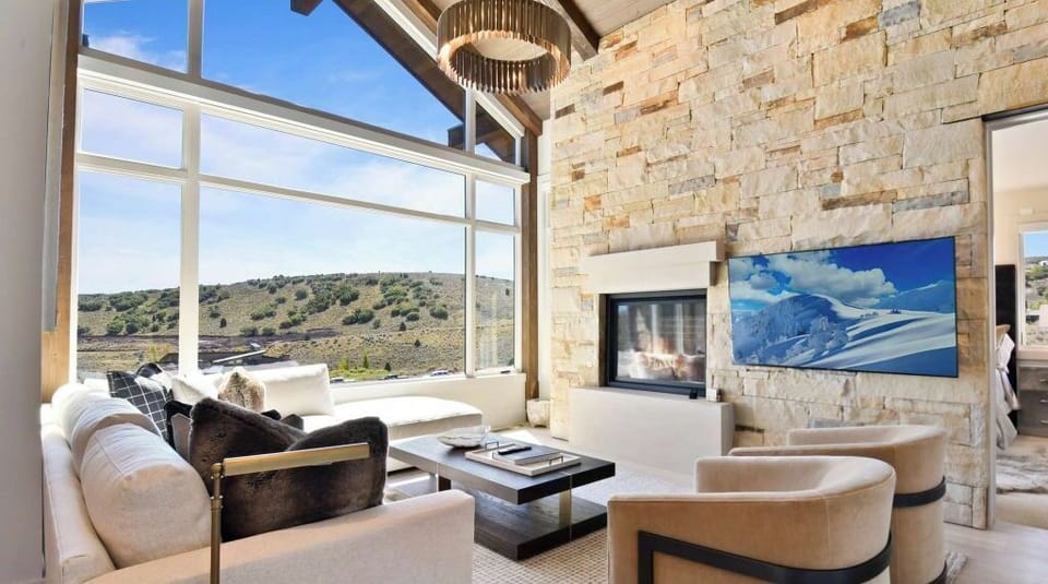 Great room is accented by a vaulted ceiling & cozy fireplace with stone wall.