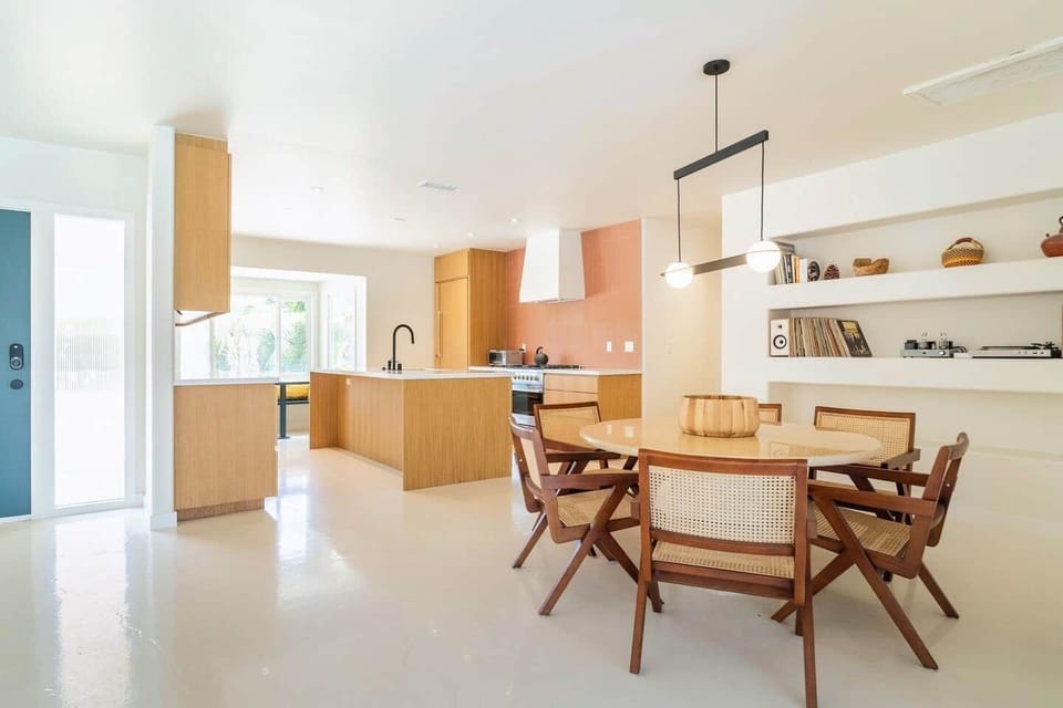 Another angle of the dining room with kitchen in the background. Record, puzzle, board game and book shelf.