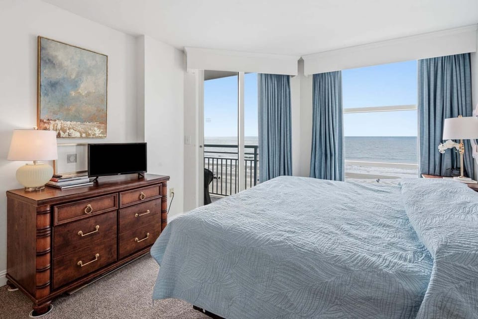 Bedroom with a blue quilt and a dresser TV at Seaside Resort 503, a 3-bedroom Crescent Beach rental