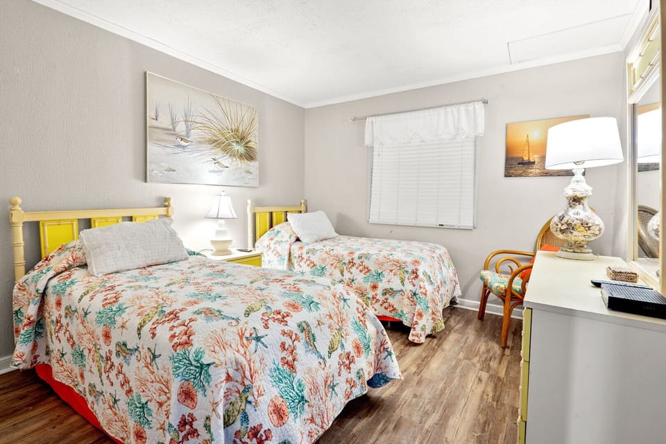 Two beds with floral bedding and a desk by the window at Windy Village A4, a Windy Hill vacation rental
