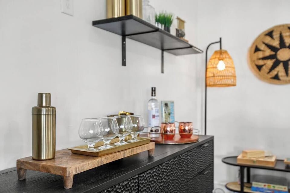 Modern bar setup with glassware and a cocktail shaker on a textured black cabinet.