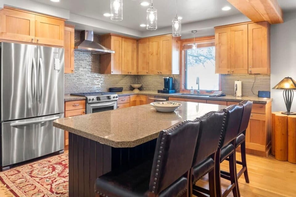 The fully equipped kitchen has stainless steel appliances, ample counter space, and a spacious kitchen island with bar stool seating for four.