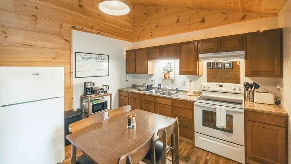 Kitchen with full size refrigerator, electric stove top, oven, toaster, coffee maker, kettle and microwave and a four seat dining table