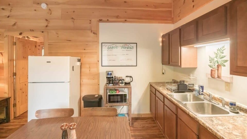 Kitchen with full size refrigerator, electric stove top, oven, toaster, coffee maker, kettle and microwave and a four seat dining table