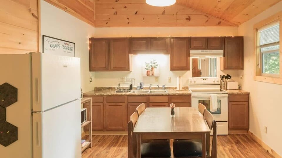 Kitchen with full size refrigerator, electric stove top, oven, toaster, coffee maker, kettle and microwave and a four seat dining table