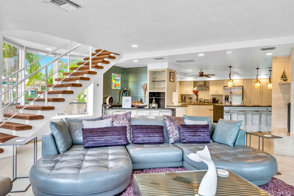 The spacious living room features outstanding views of the heated pool and waterway, a bar and a fire place.