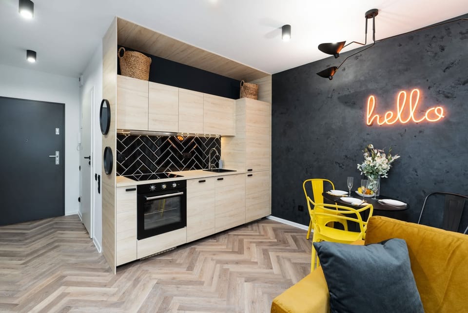 A stylish hallway with a "hello" neon sign, yellow chairs, and dark accent walls.