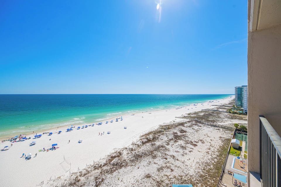 Turquoise waters stretch along the coast as you relax under the clear blue sky from your balcony view