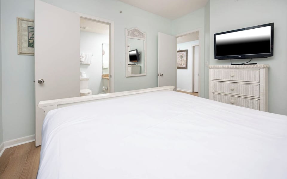 Relax in this guest bedroom featuring a queen bed, a TV for entertainment, and soft colors enhancing your stay