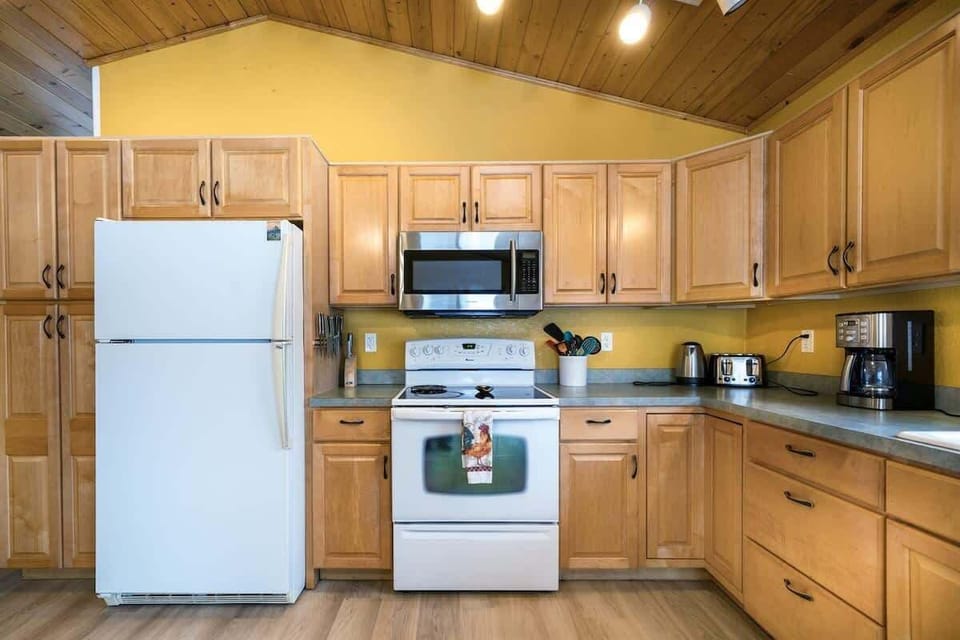 Fully equipped kitchen with cooking basics, spices, drip coffee maker, dishware/flatware, paper towels/trash bags blender, and toaster.