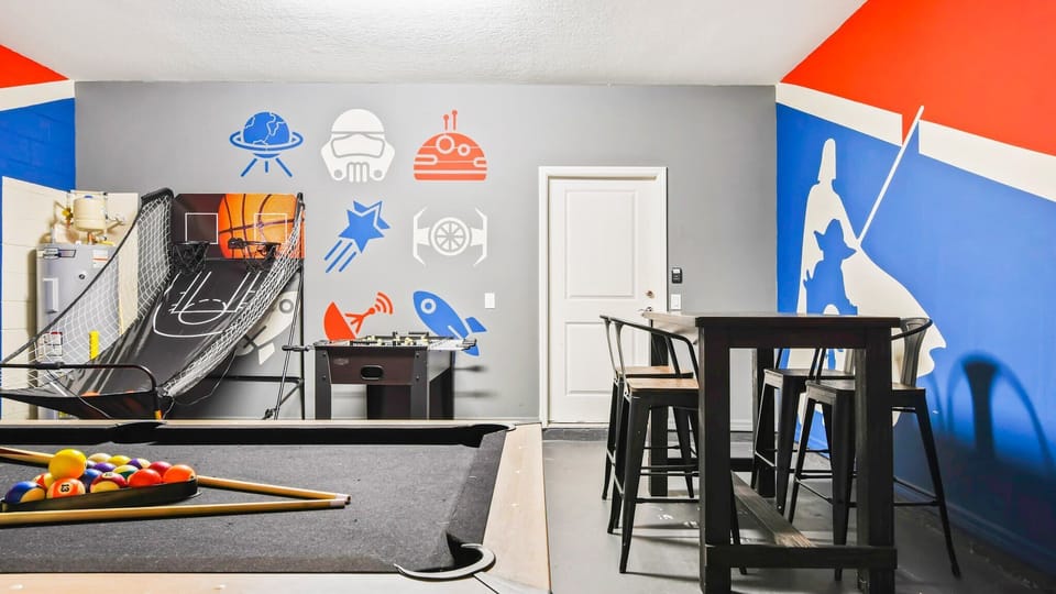 Epic game room with sports and sci-fi decor, pool table, basketball, foosball, and bar seating.