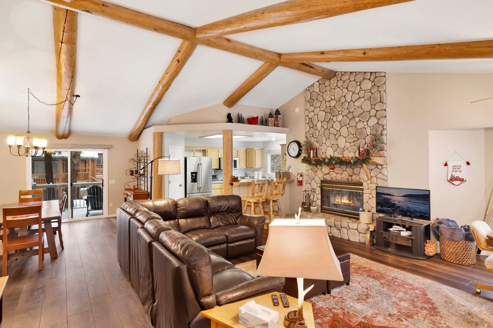 Cozy mountain living room with a stone fireplace, comfy seating, and smart TV—perfect for relaxing evenings, movie nights, and warm cabin vibes after outdoor adventures.