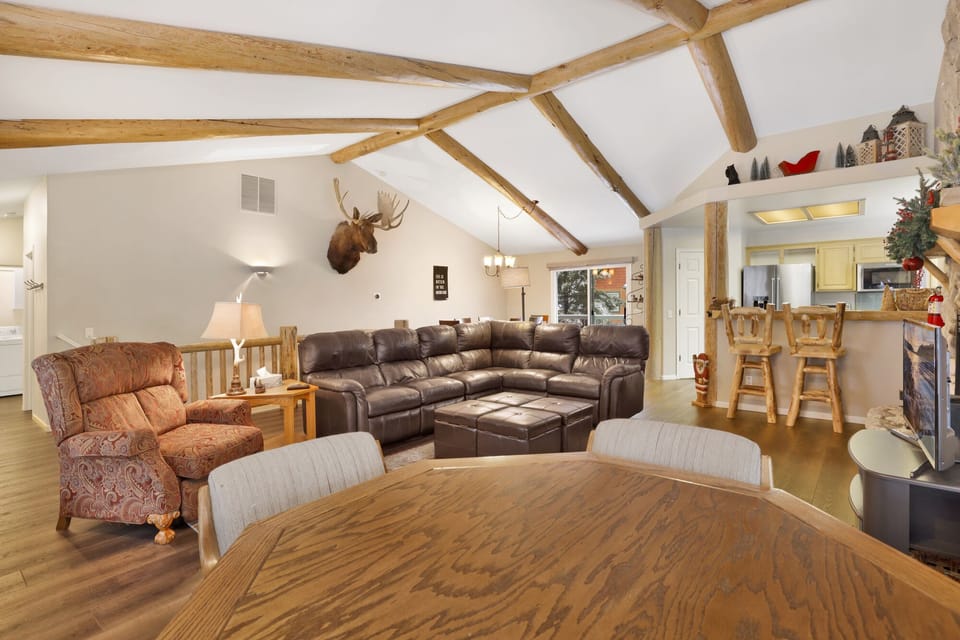 Cozy mountain living room with a stone fireplace, comfy seating, and smart TV—perfect for relaxing evenings, movie nights, and warm cabin vibes after outdoor adventures.