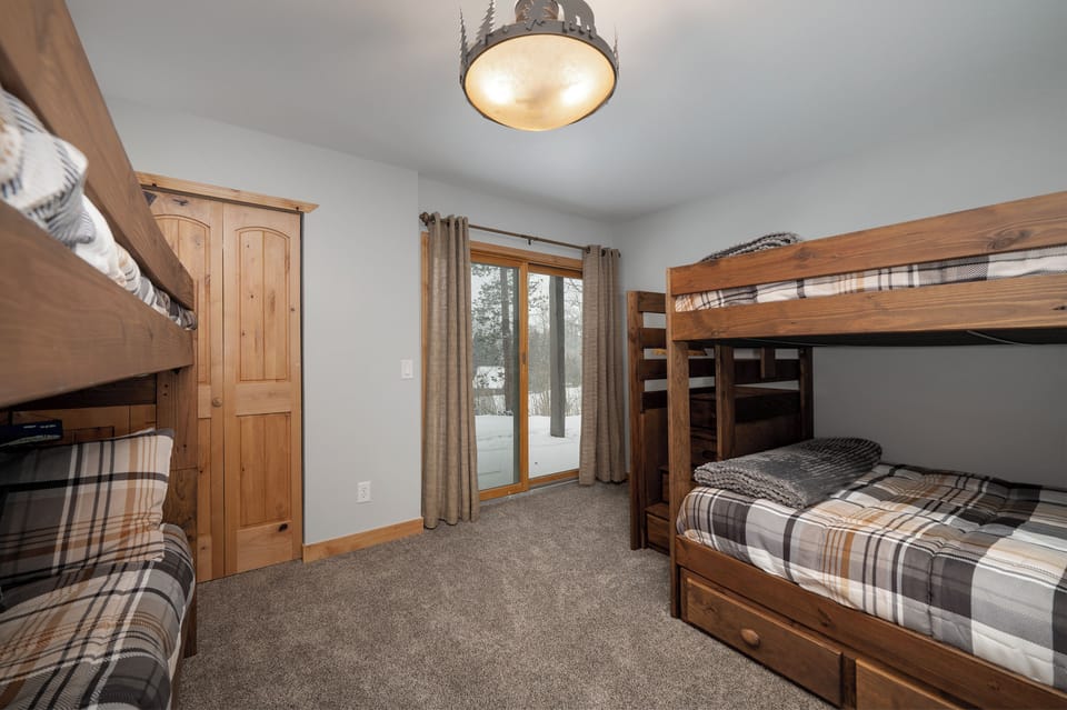Your cozy bunk room features rustic wood furniture and plaid linens, creating the perfect mountain lodge atmosphere for restful nights.