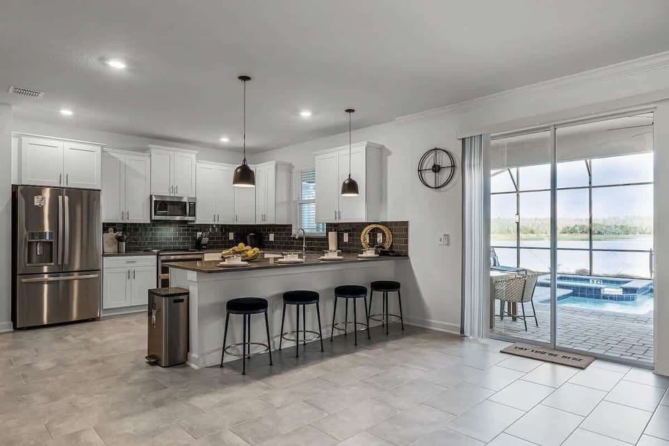 Our kitchen is airy and white, with a charcoal backsplash and black velvet seats at the counter bar.