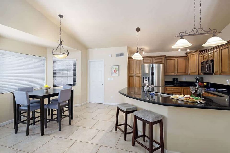 Fully equipped kitchen with stainless steel appliances, breakfast bar seating, and dining table with seating for 4 guests.
