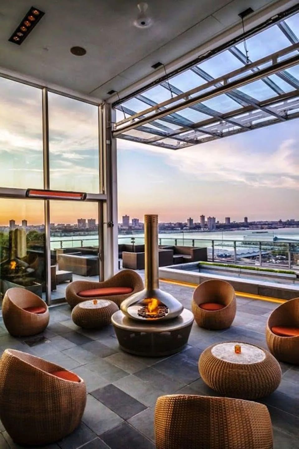 Sip cocktails fireside while sunset city views glow outside.
