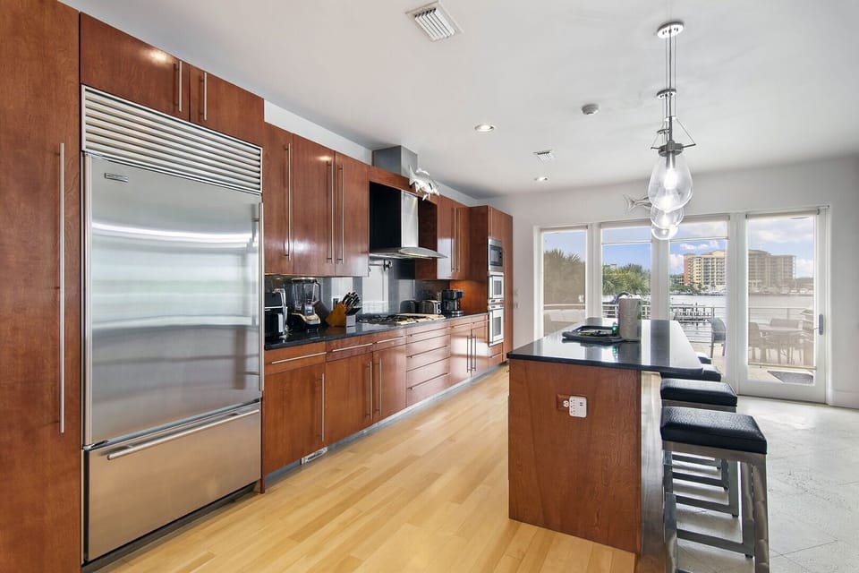 Sleek kitchen view w/ stainless appliances & warm wood finishes