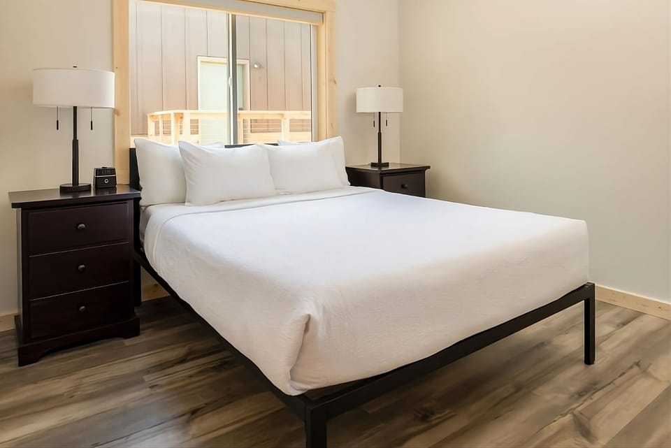 Sink into a plush bed framed by warm, modern nightstands.