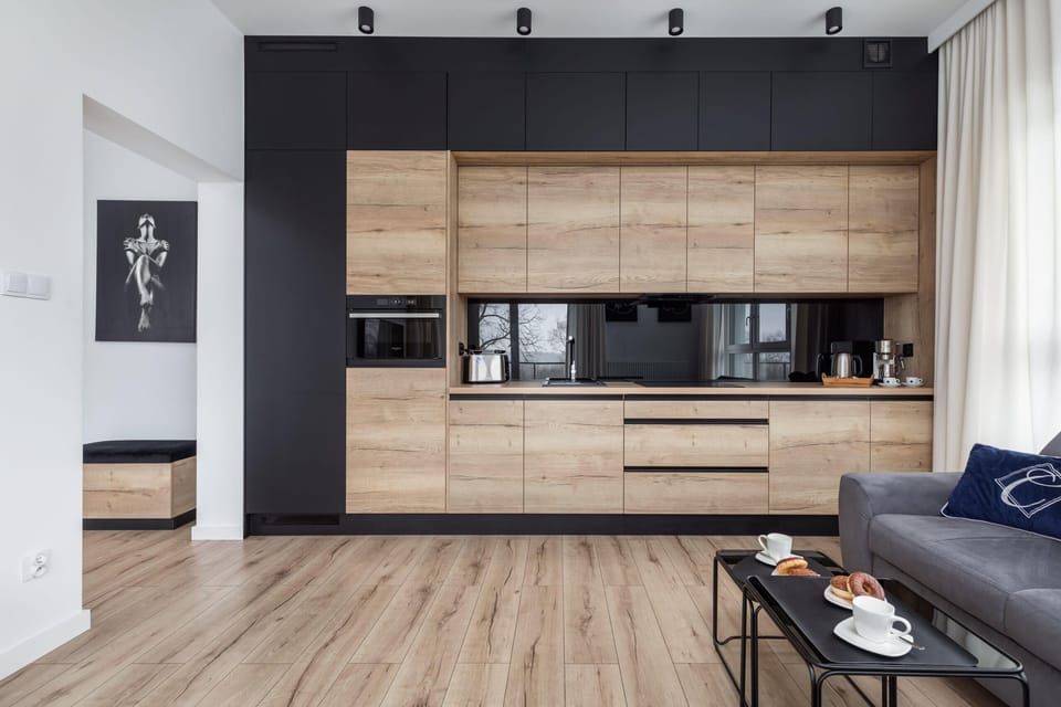A stylish kitchen and dining area with wood and black finishes, accompanied by a sleek dining table.