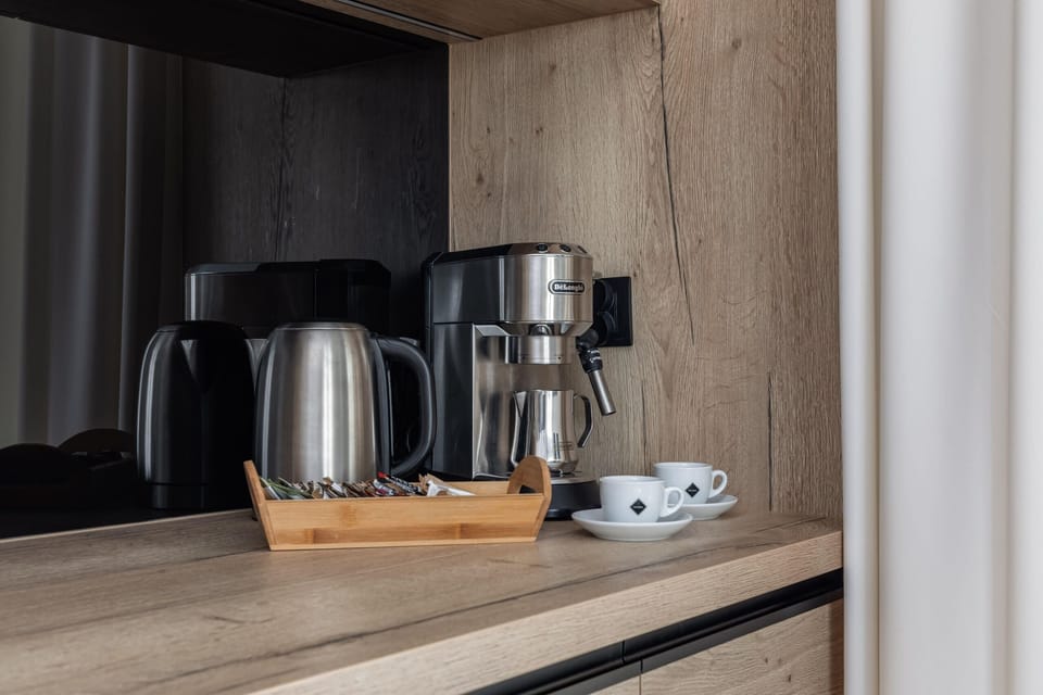 A kitchen corner featuring a coffee maker, electric kettle, and modern cabinetry.