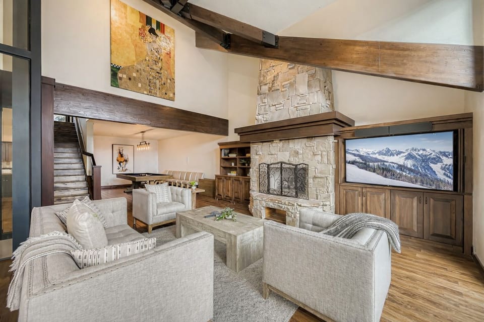 Gather around your cozy stone fireplace in this elegant living room, where mountain views and exposed beams create the perfect alpine retreat atmosphere.