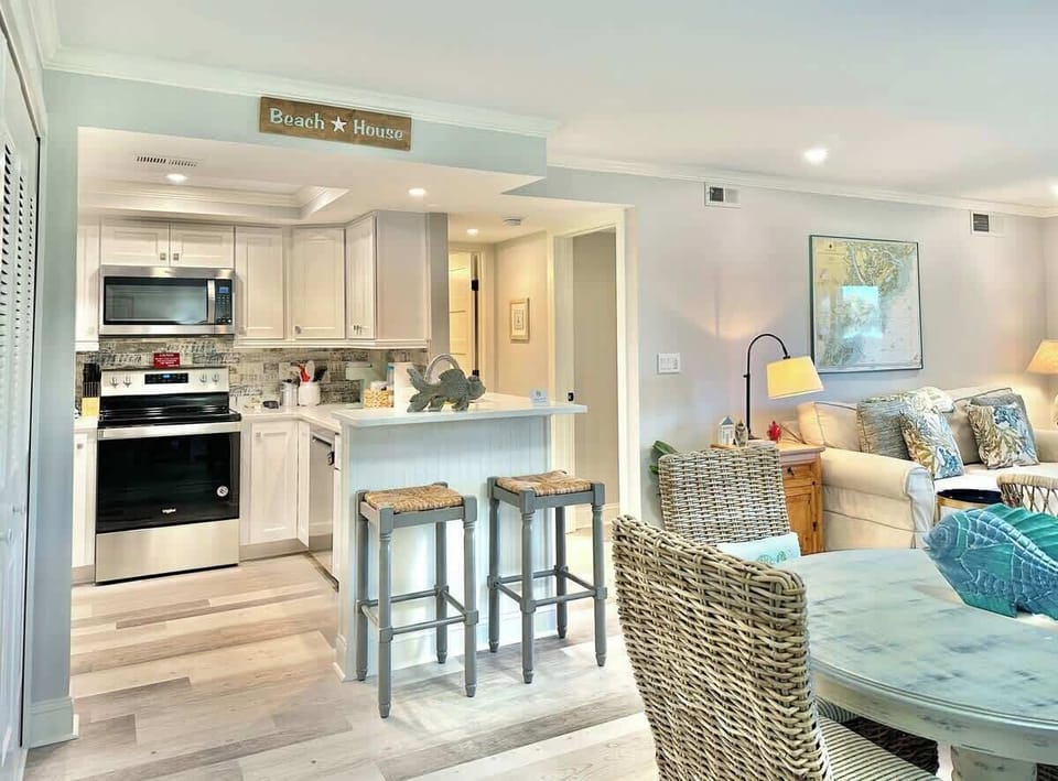 Bright kitchen and living area with coastal decor and a breakfast bar.