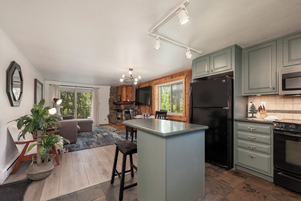 Your open-concept retreat blends rustic charm with modern comfort, featuring sage-green cabinetry, granite counters, and cozy living spaces.