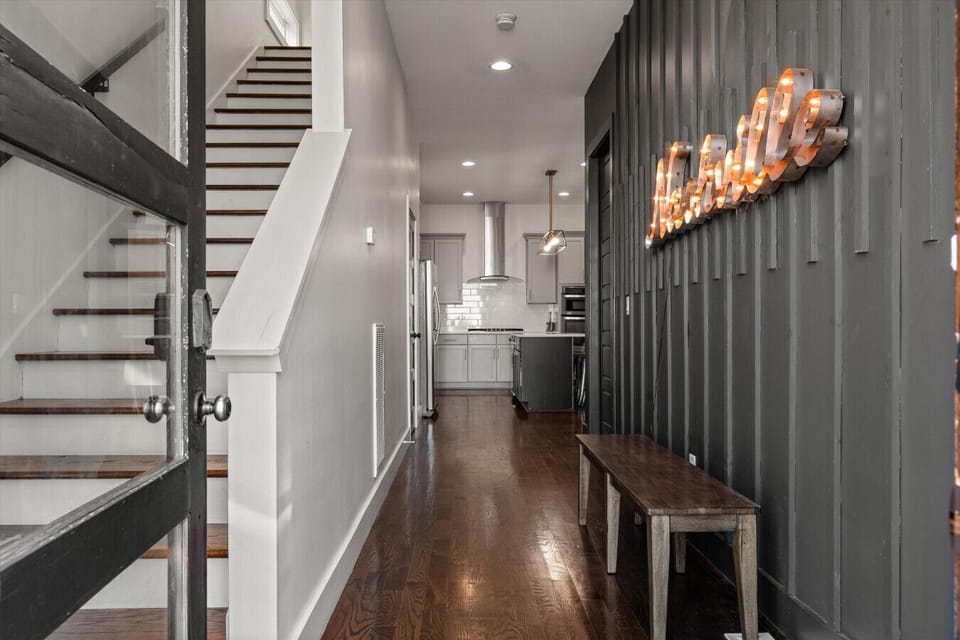 Step inside to warm industrial lighting, rich wood tones, and a clear sight line straight through to the kitchen.