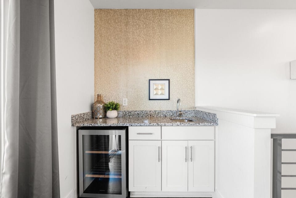The wet bar on the third level — a mini fridge, and a sink. Pour up before heading to the rooftop.