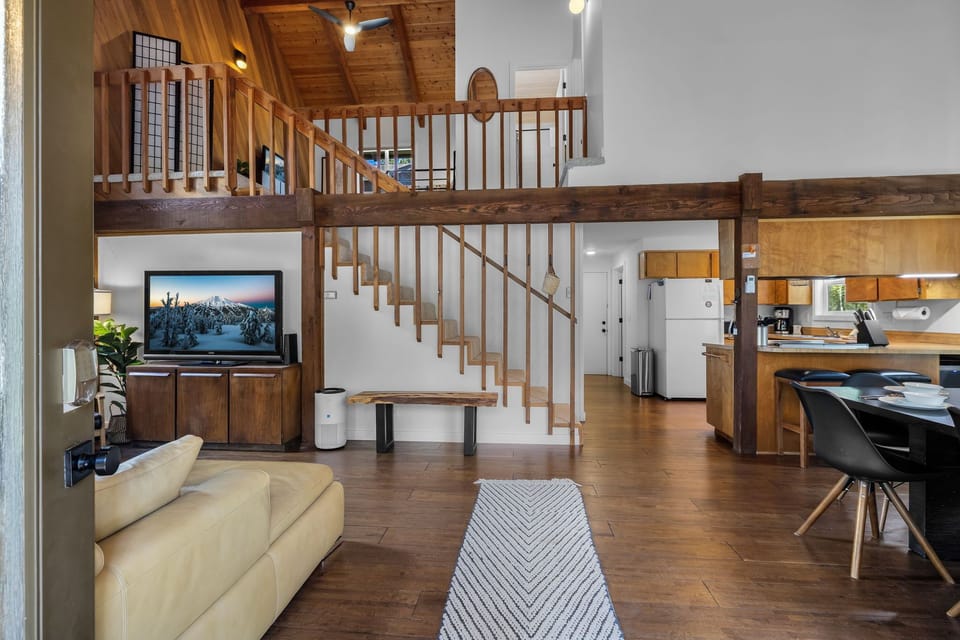 Relax in this inviting open-plan space with soaring wooden ceilings, a cozy living area, and a lofted retreat above. Your mountain getaway features warm timber accents, modern amenities, and comfortable seating for memorable evenings.