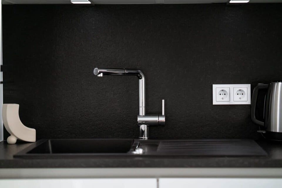 Sleek kitchenette with modern amenities and chic black backsplash for easy meal prep.