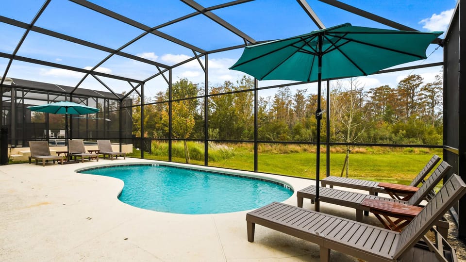 Private screened-in pool with loungers, umbrellas, and peaceful nature views.