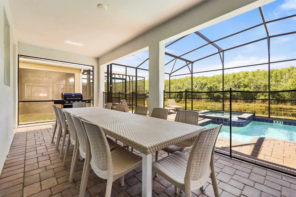 Dine outdoors by the pool with serene views of lush greenery, perfect for gatherings and relaxation.