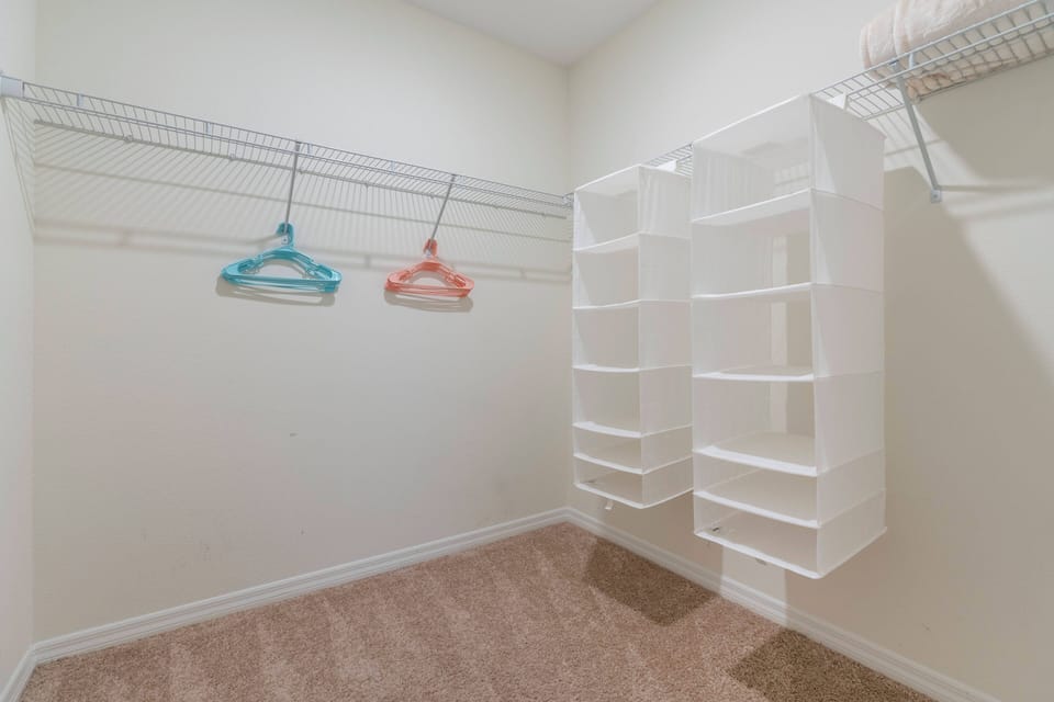 This spacious closet offers neat white shelving and hanging rods, providing ample room for your belongings. Colorful hangers add a playful touch, ensuring everything stays organized and easily accessible throughout your stay.