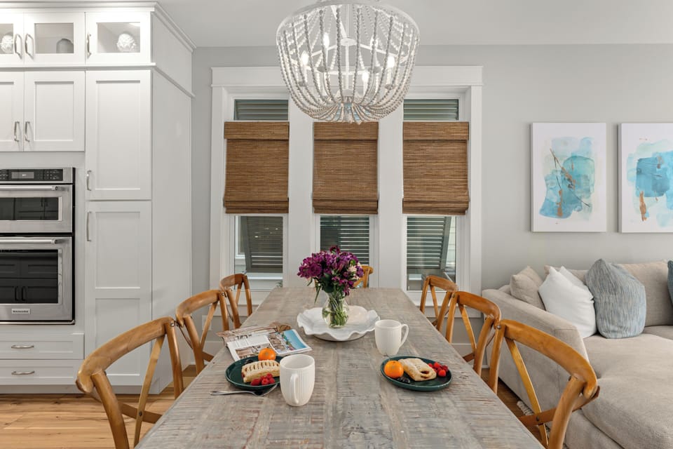 Elegant wooden dining table set for a meal under a beaded chandelier.