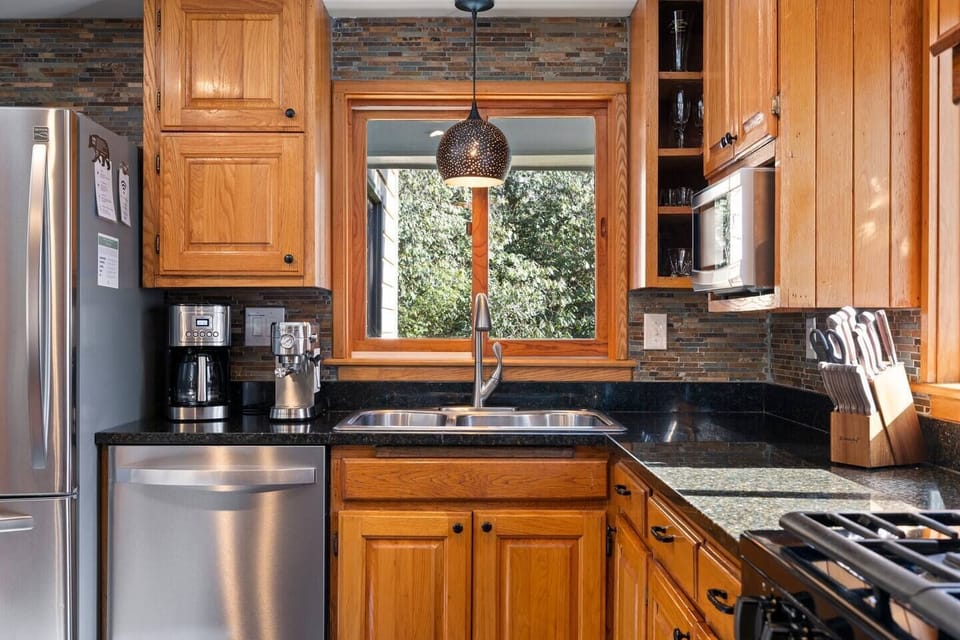 The fully equipped kitchen features stainless steel appliances, an espresso and drip coffee maker, a gas range, and an in-counter griddle. A spacious pantry provides shelving for groceries and easy access to cooking utensils and grilling essentials. 