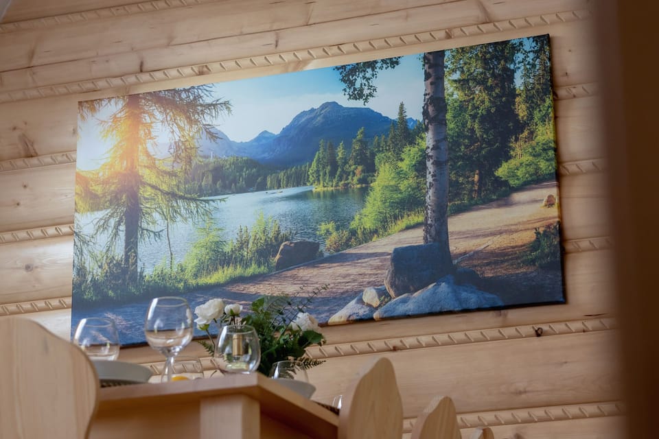 A dining room decorated with a painting of a serene mountain and forest landscape.
