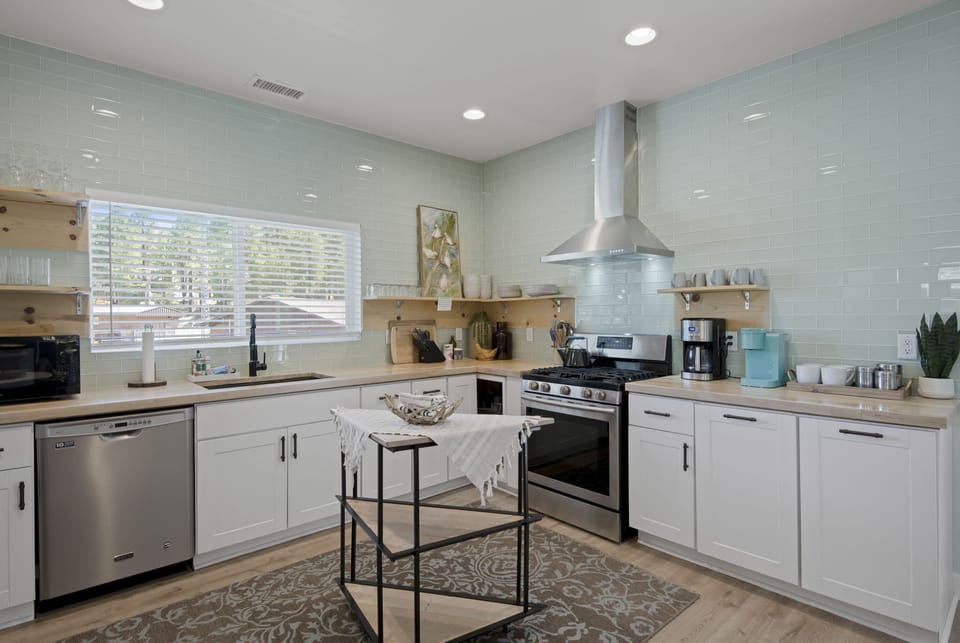The kitchen is upgraded with butcher block, cabinets, and amazing glass tile
