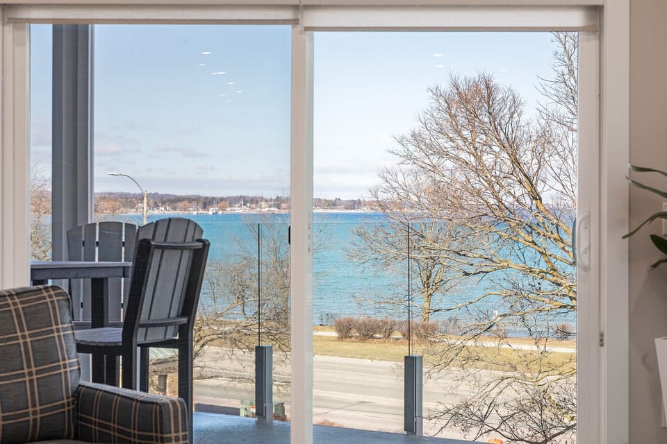 Outdoor balcony chairs and Grand Traverse Bay seen through sliding glass doors.
