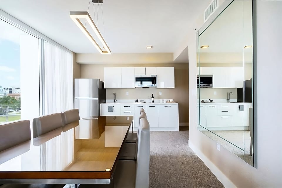 Gather for meals at a glossy table beside the sunny kitchenette.